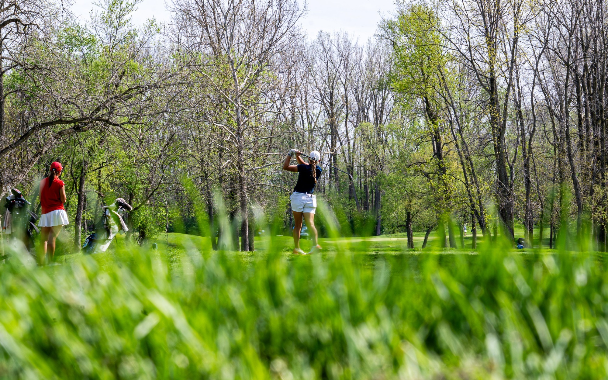 Elaine Grant golfing from afar, she is pictured in blue polo and white bottoms at GLVC Golf Tournament