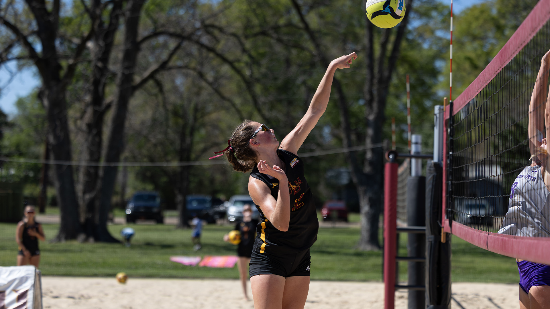 Beach volleyball player Brooke Bankston hitting the volleyball over the net