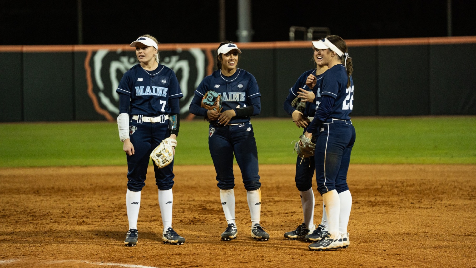 Maine softball infielders stand near the pitcher's circle.