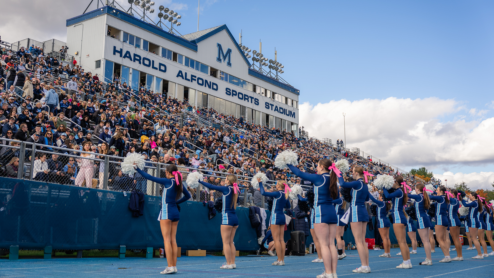 Cheerleaders cheer with the crowd at a football game