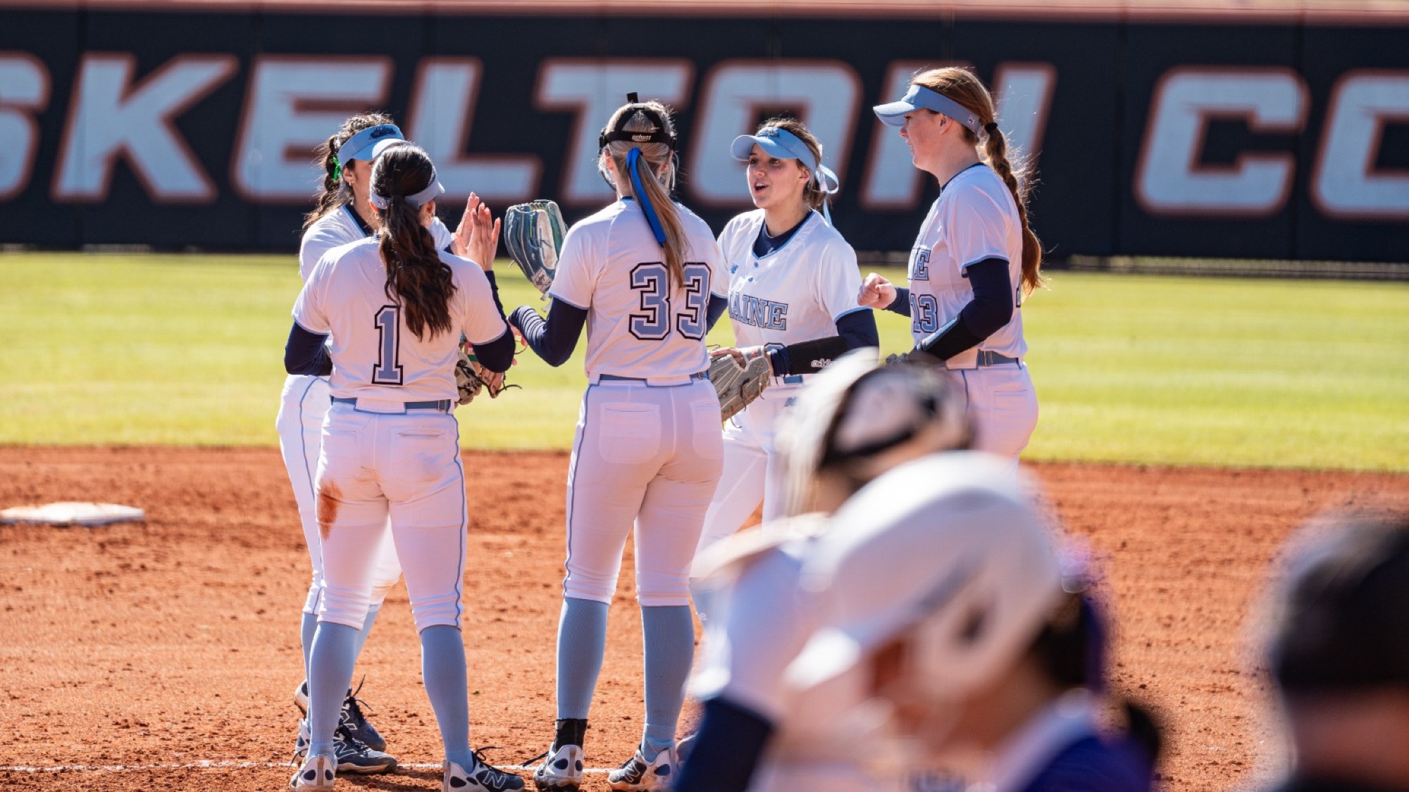 Maine softball huddles in the pitching circle.