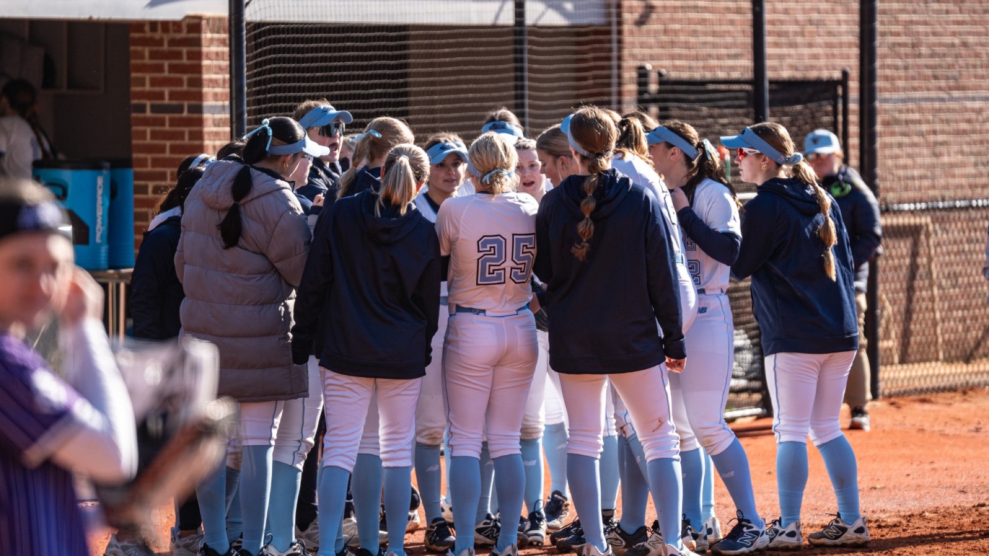 Maine softball huddles in between innings.