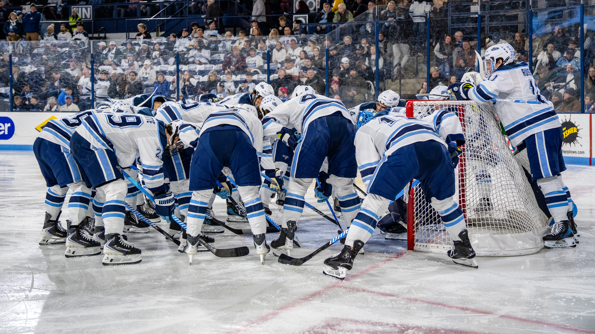 Maine men's ice hockey huddles around the net pregame.
