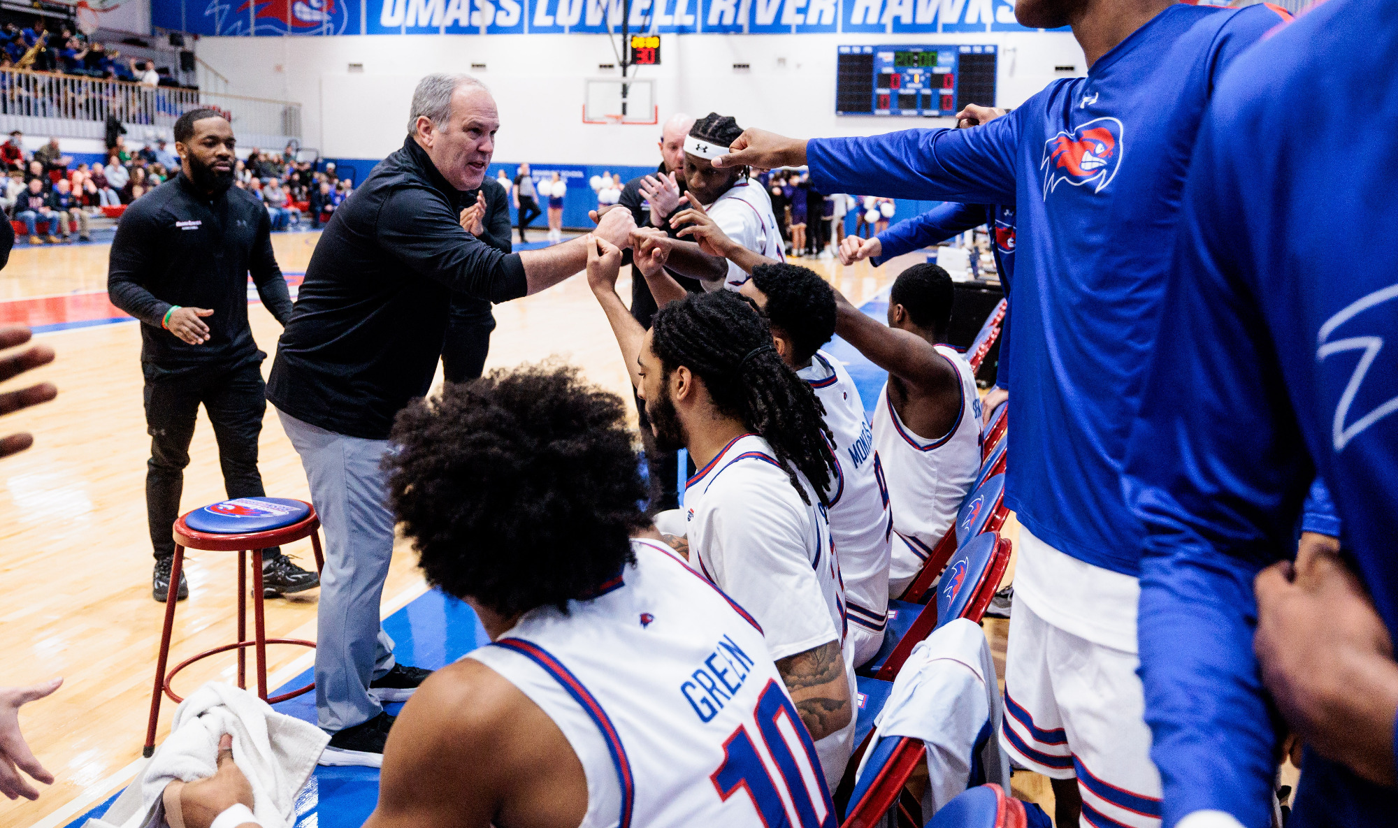 UMass Lowell Head Coach Pat Duquette in huddle with team.