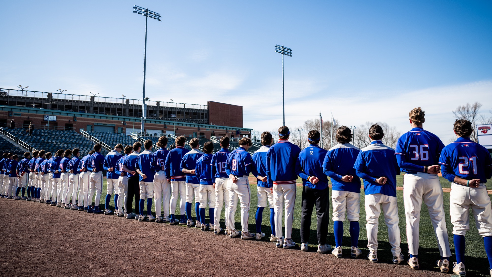 UMass Lowell baseball players lined up on the field of Edward A. LeLacheur Park before the national anthem is played 