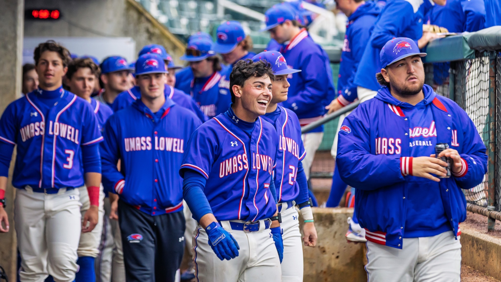 UMass Lowell baseball player happy in the dugout with his other River Hawk teammates after hitting a home run in the third inning