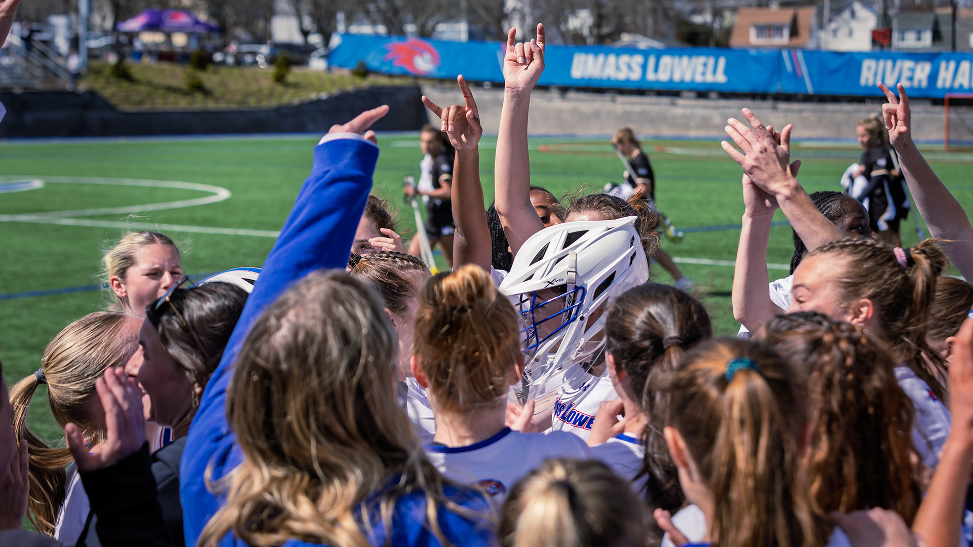 Women's lacrosse huddled up with hands in the air prior to game against UMBC