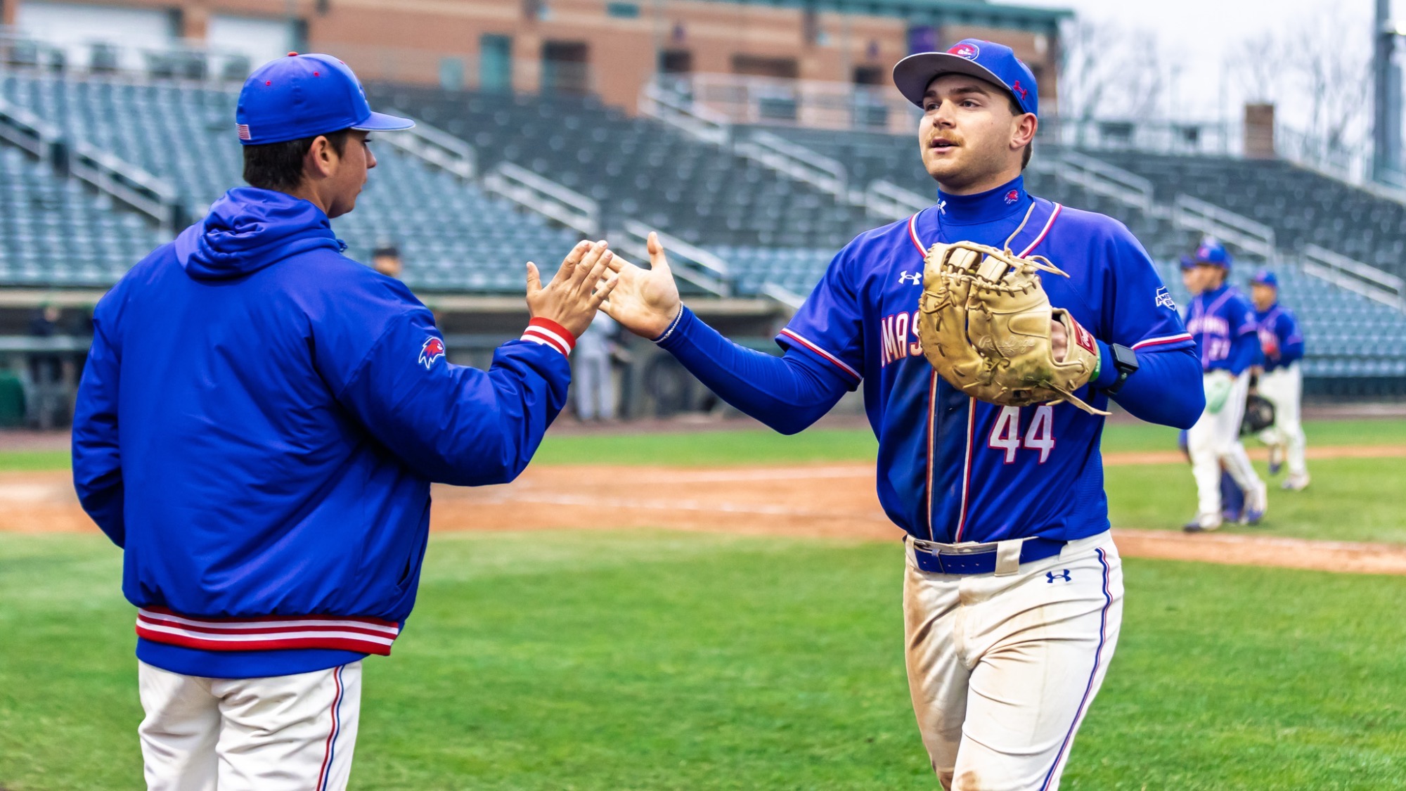 UMass Lowell baseball players high-fiving on their way to the dugout after finishing up an inning