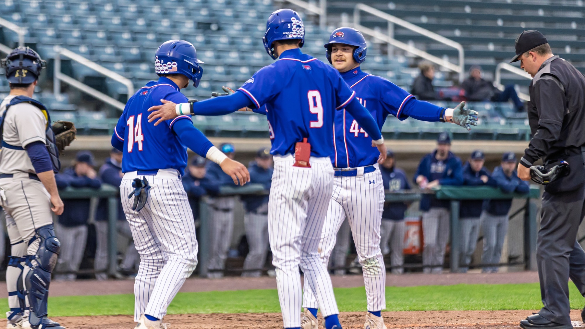 UMass Lowell baseball players celebrating at home plate after a home run was hit to extend the lead