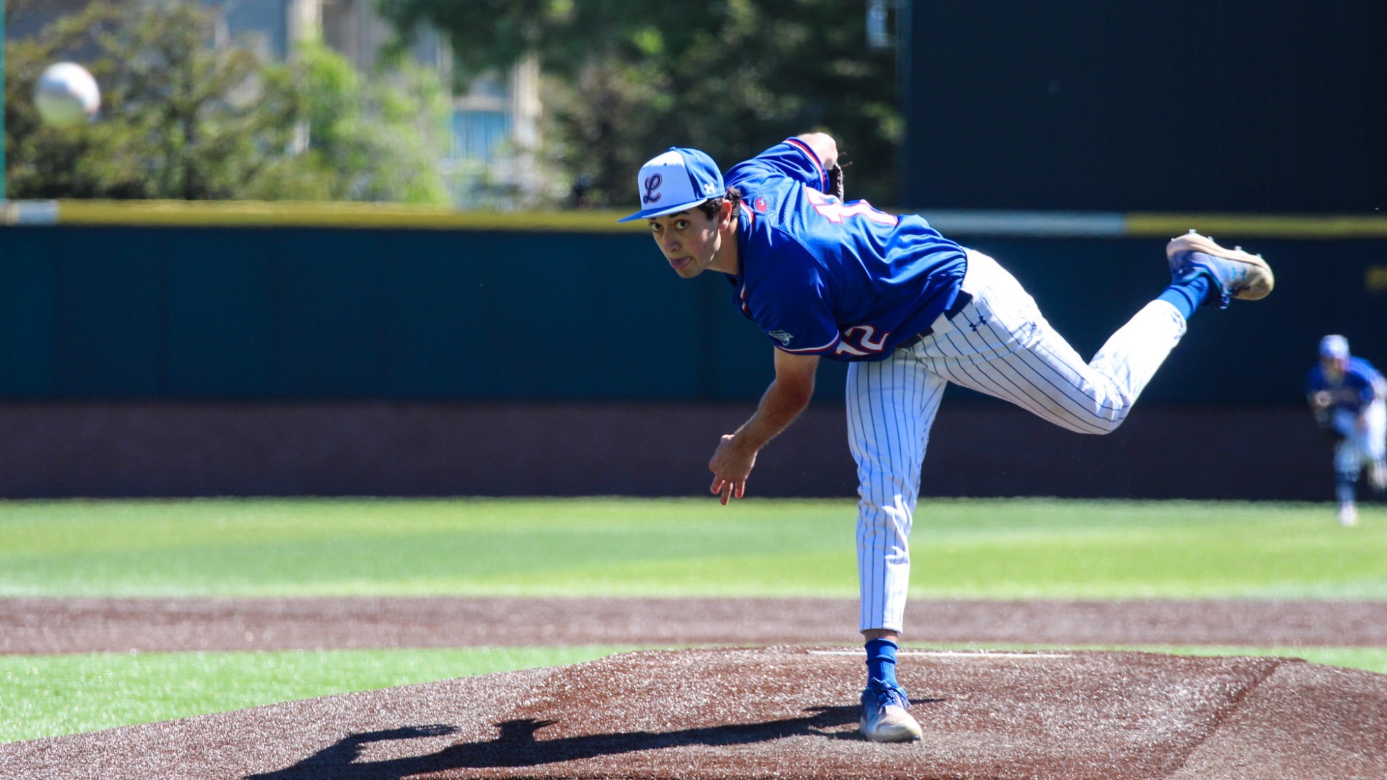UMass Lowell baseball pitcher tossing the ball on the mound down to the batter's box during live play