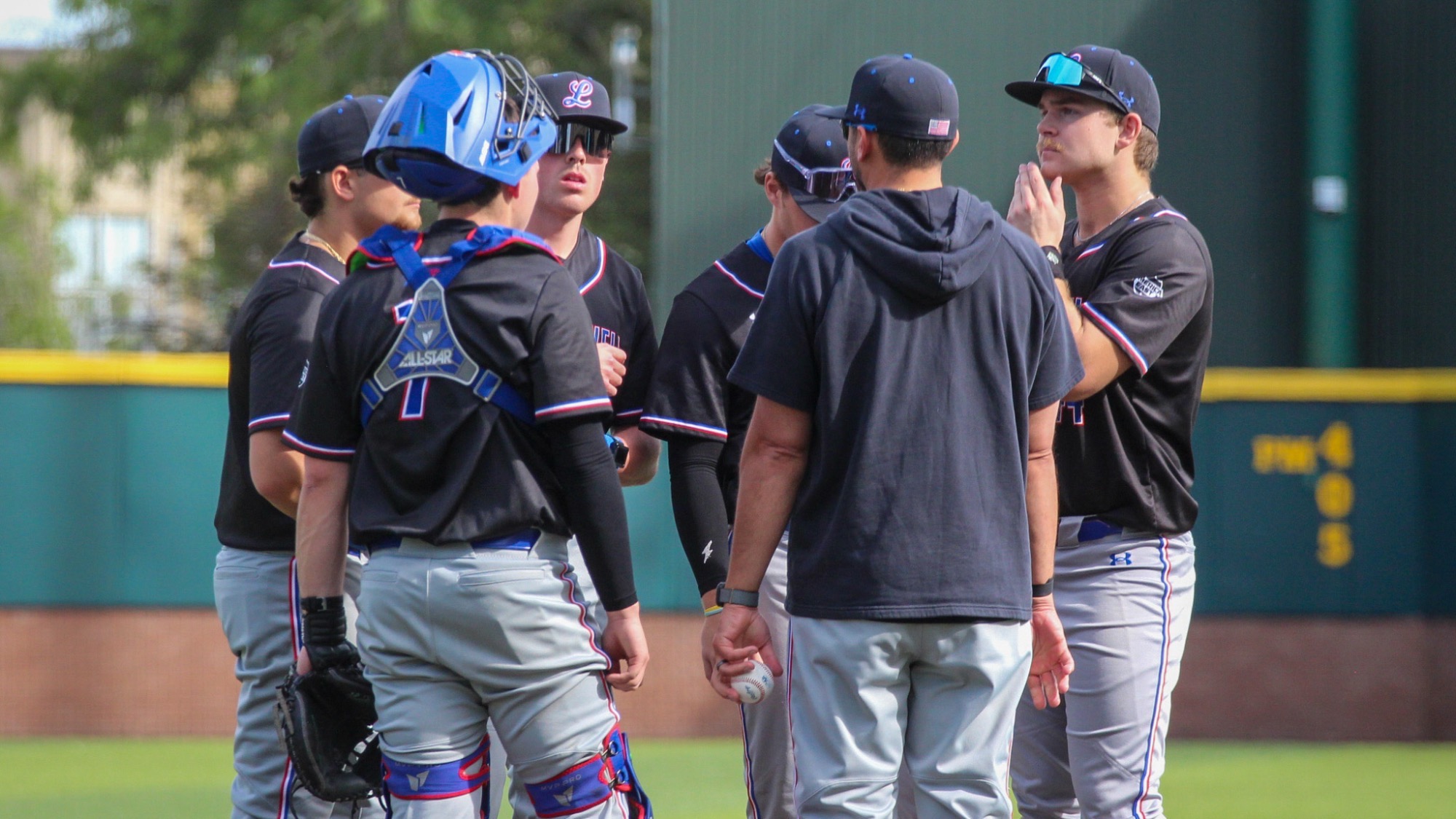 UMass Lowell baseball players on the mound talking during an inning about adjusting their overall scheme.