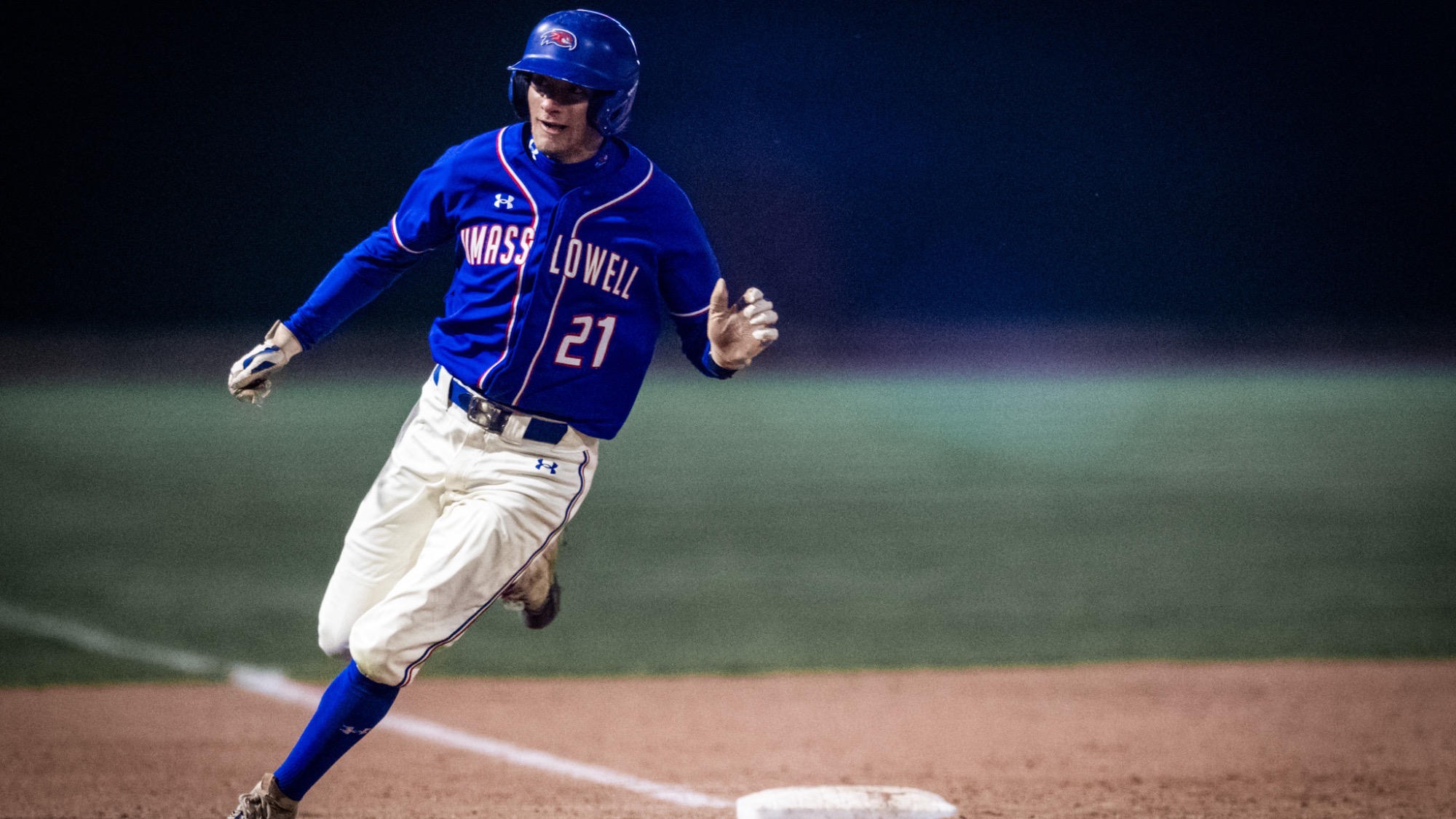 UMass Lowell baseball player looking to round third base after advancing on a hit into play