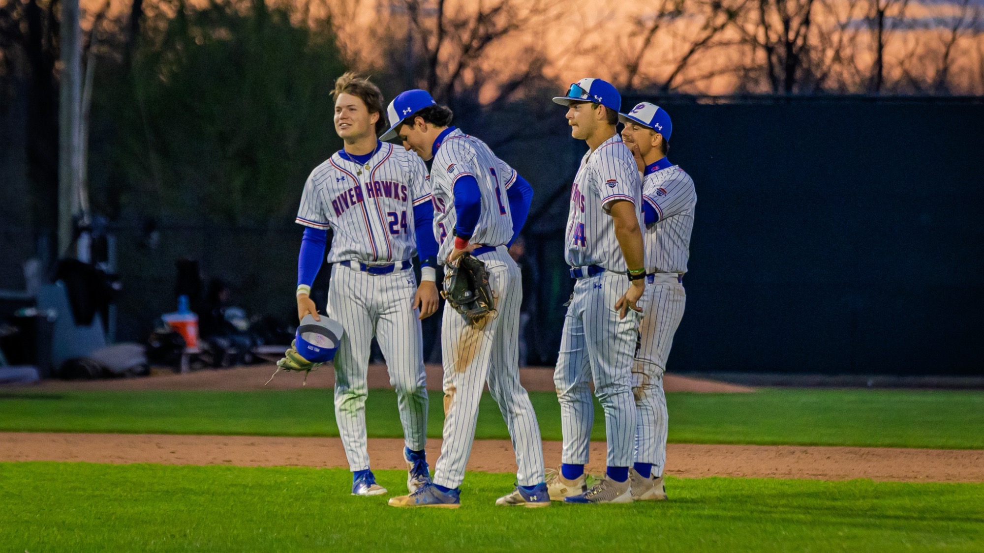 UMass Lowell baseball players on the field of Edward A. LeLacheur Park waiting for the new pitcher to warm up