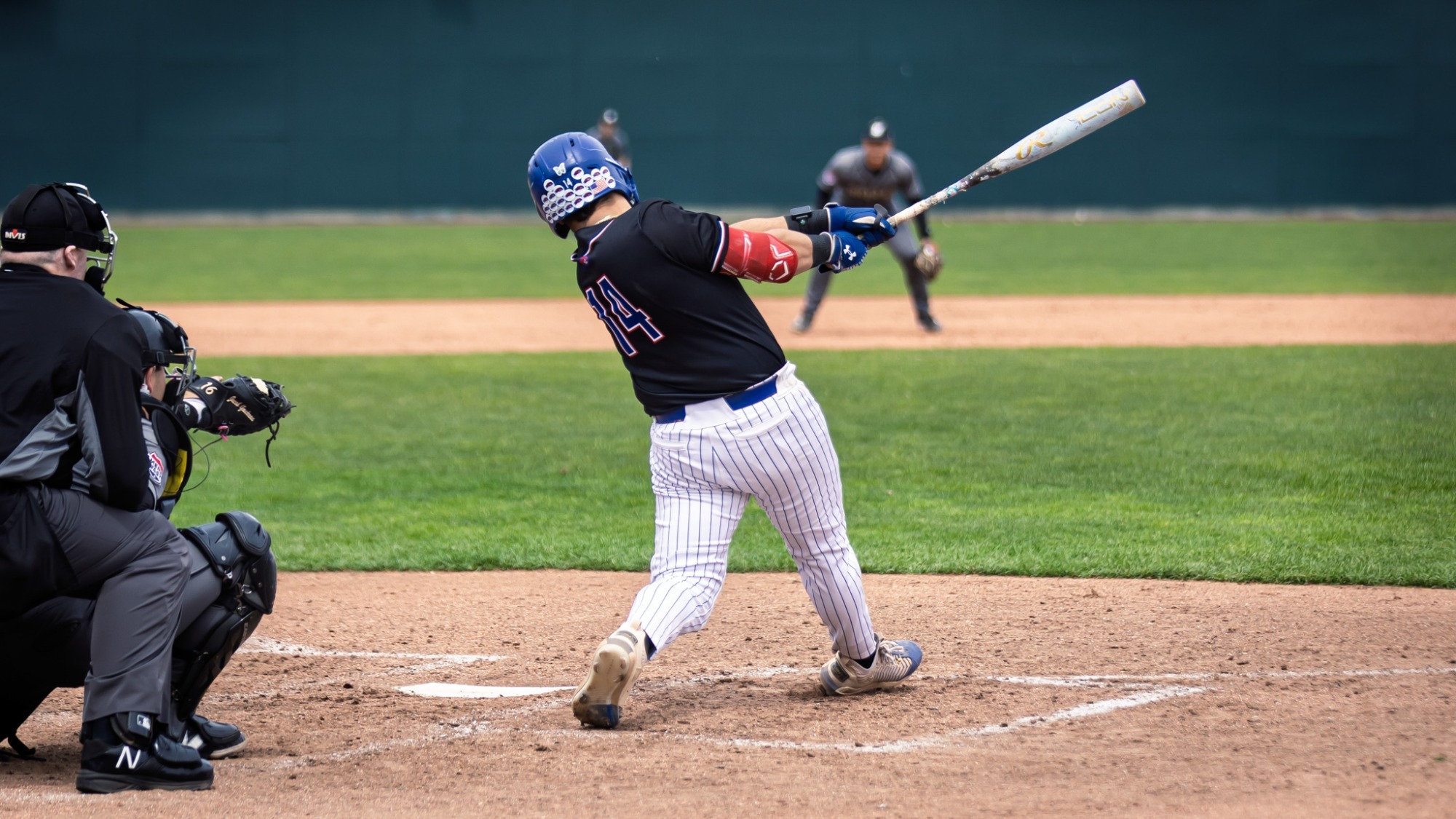 UMass Lowell baseball player swinging the bat during his plate appearance as the ball is thrown down into the strike zone 