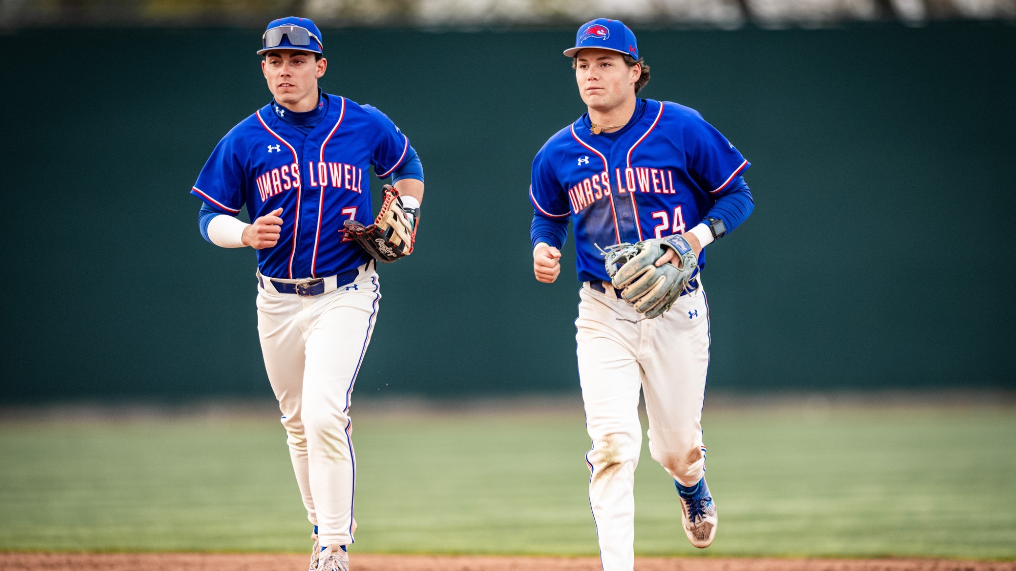 Two UMass Lowell baseball players running off the field and getting ready for their at-bats after the inning ended 