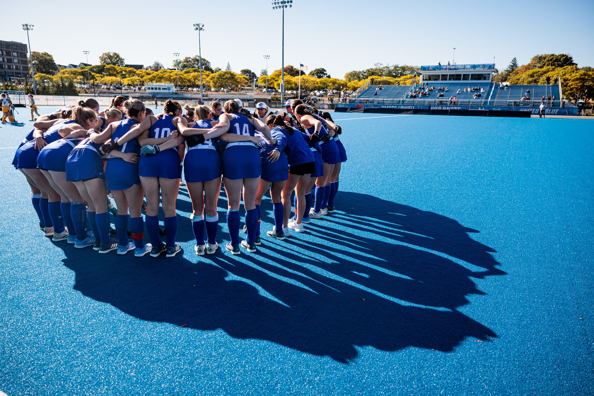 Field Hockey team huddling on blue field