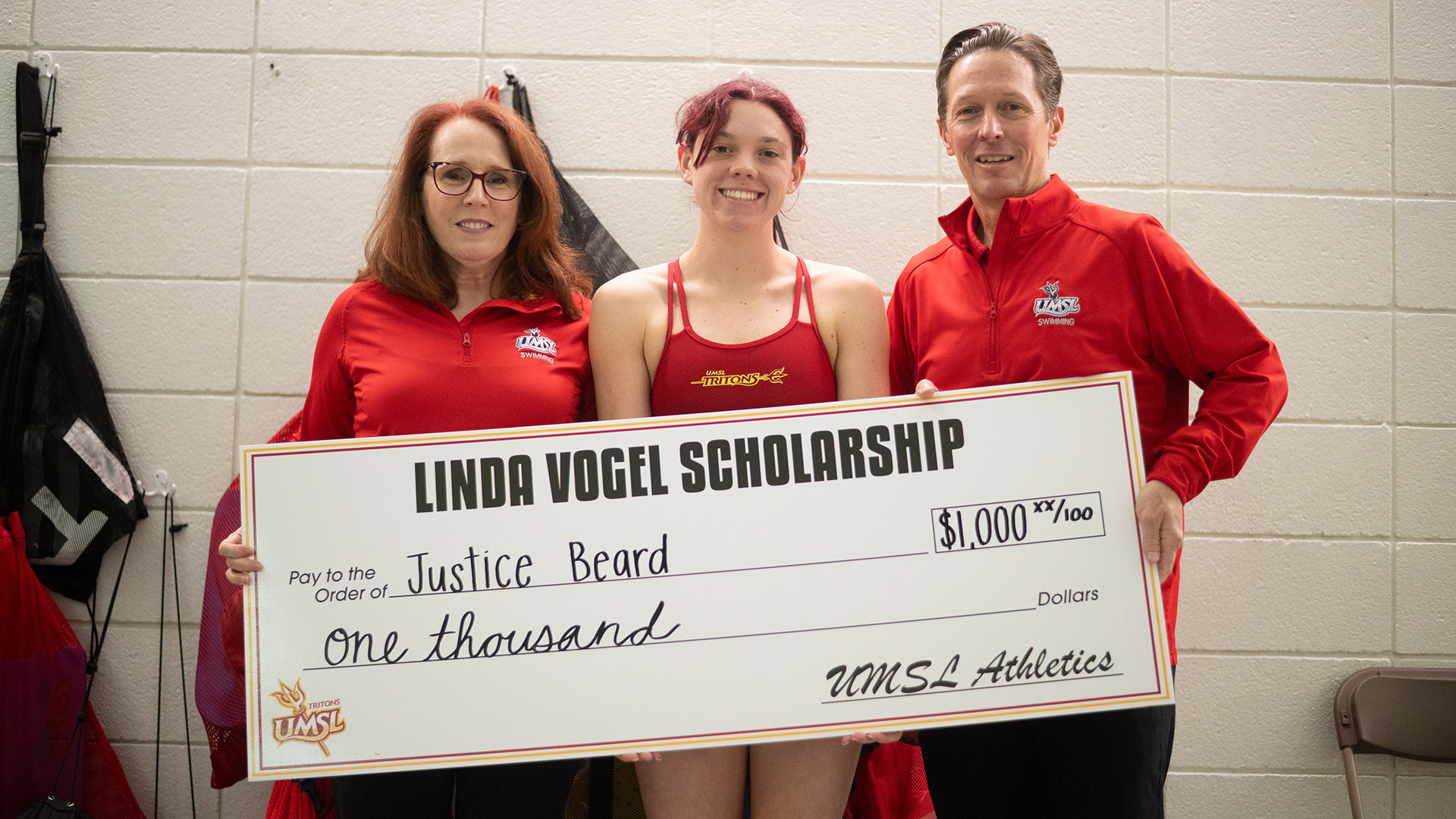 UMSL's Justice Beard was presented a check for the Linda Vogel UMSL Swimming Alumni scholarship by Tom and Michelle Lombardo