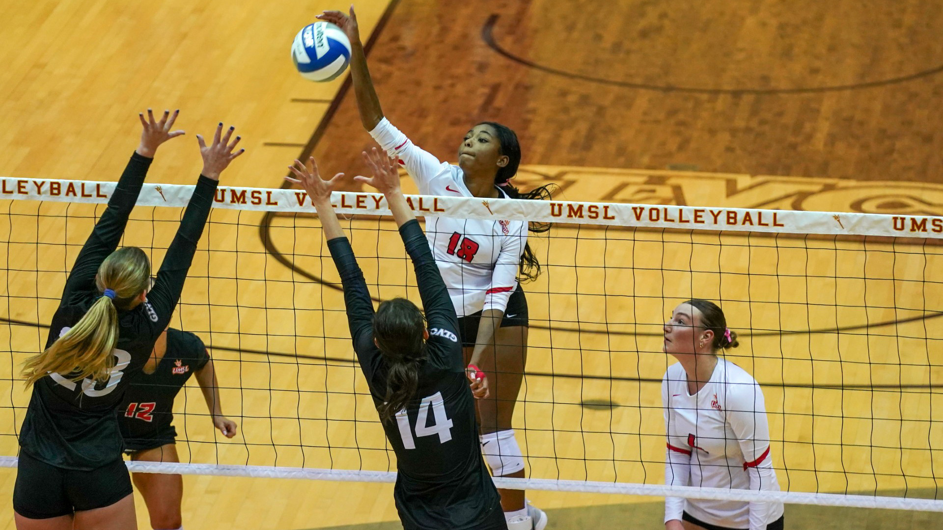Mady Gant (#18) in white jersey goes up for an attack attempt in a volleyball match against Truman State.