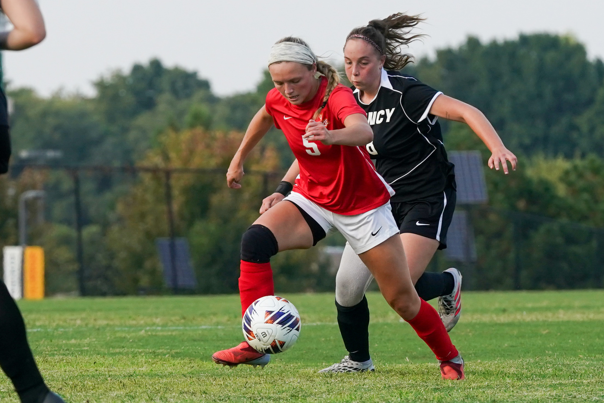 Josie Maddox dribbles the soccer ball upfield while being chased by a Quincy defender