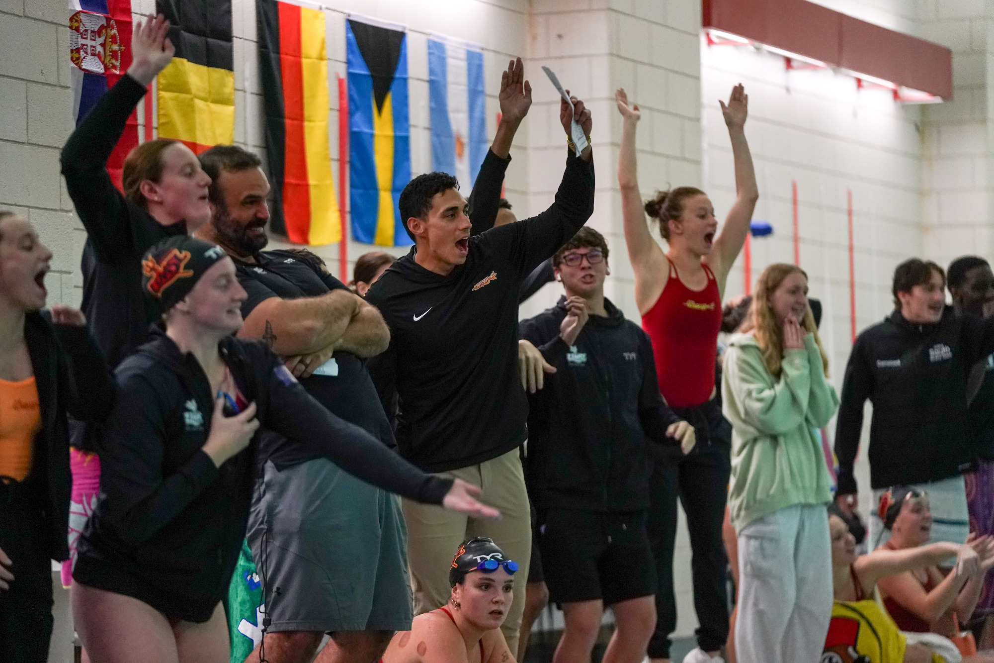 UMSL Swimmers and Coaches cheering from the sidelines during a race in a meet against Saint Louis University.