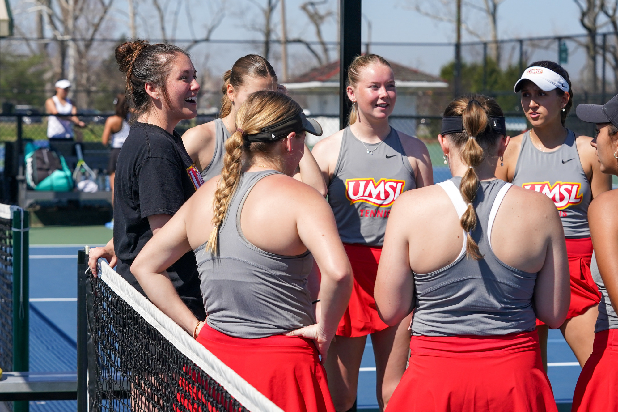 UMSL women's tennis players gather around head coach Megan Holdridge for a message