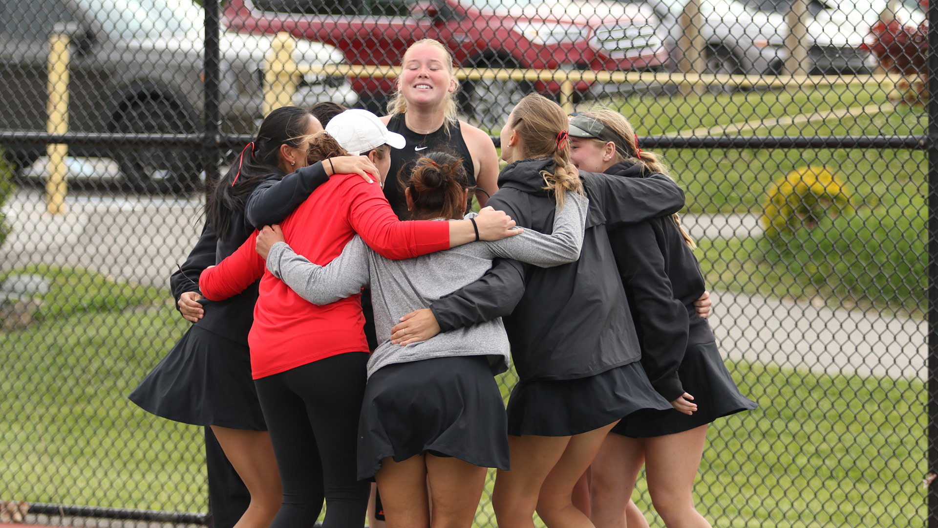 UMSL women's tennis players huddle around teammate Millie Wileman after she won the clinching match in the GLVC Championship contest against UIndy