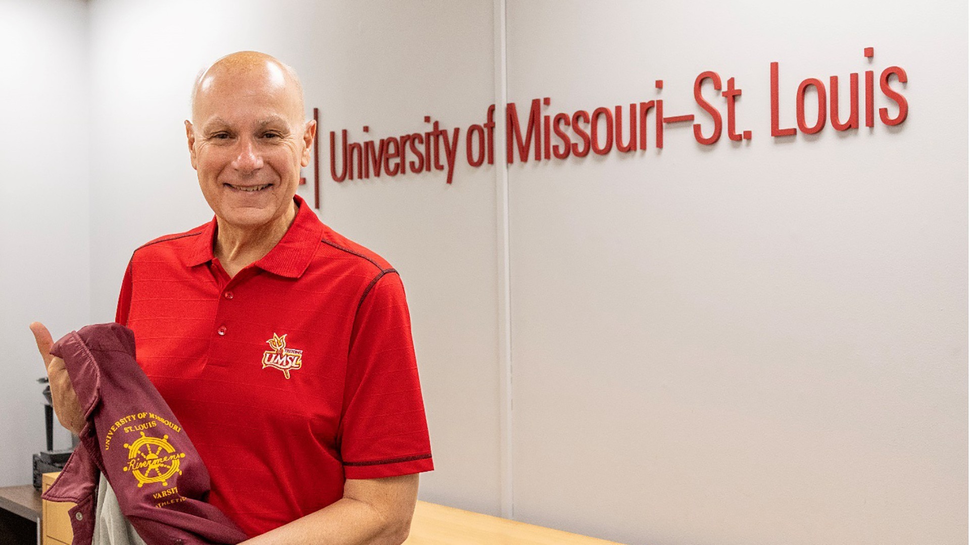 Tom Minogue holds his varsity letterman jacket from his time on the UMSL men’s tennis team in the 1970s.