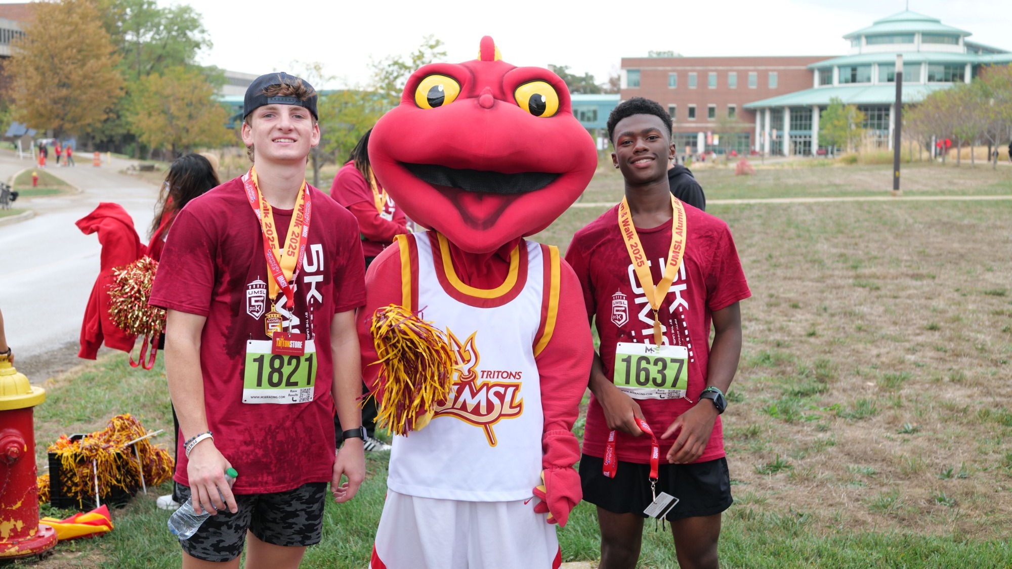 two students standing with mascot after a race.