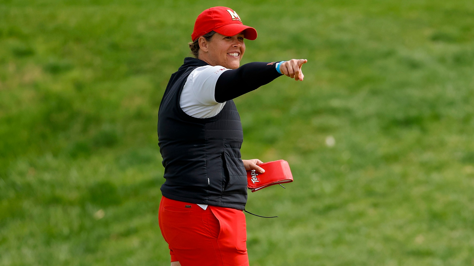 Kelly Hovland smiles and points on the golf course