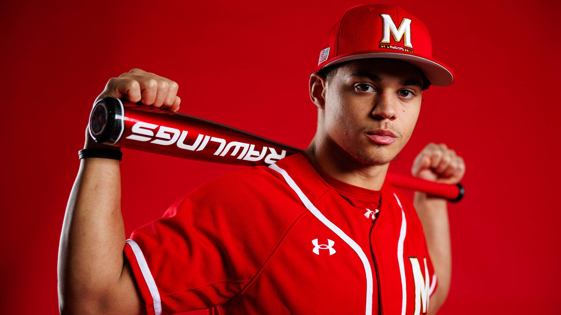 Story Cover Photo - Bud Coombs posing for the camera with red backdrop