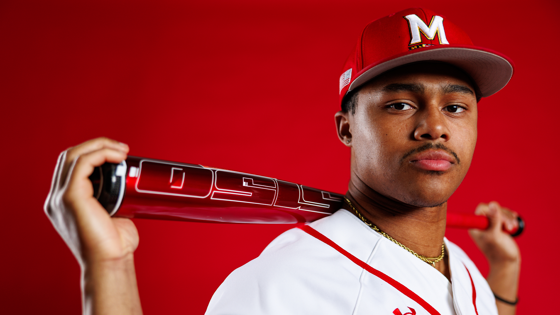 Story Cover Photo - Jordan Crosland posing in front of red background with bat in hands