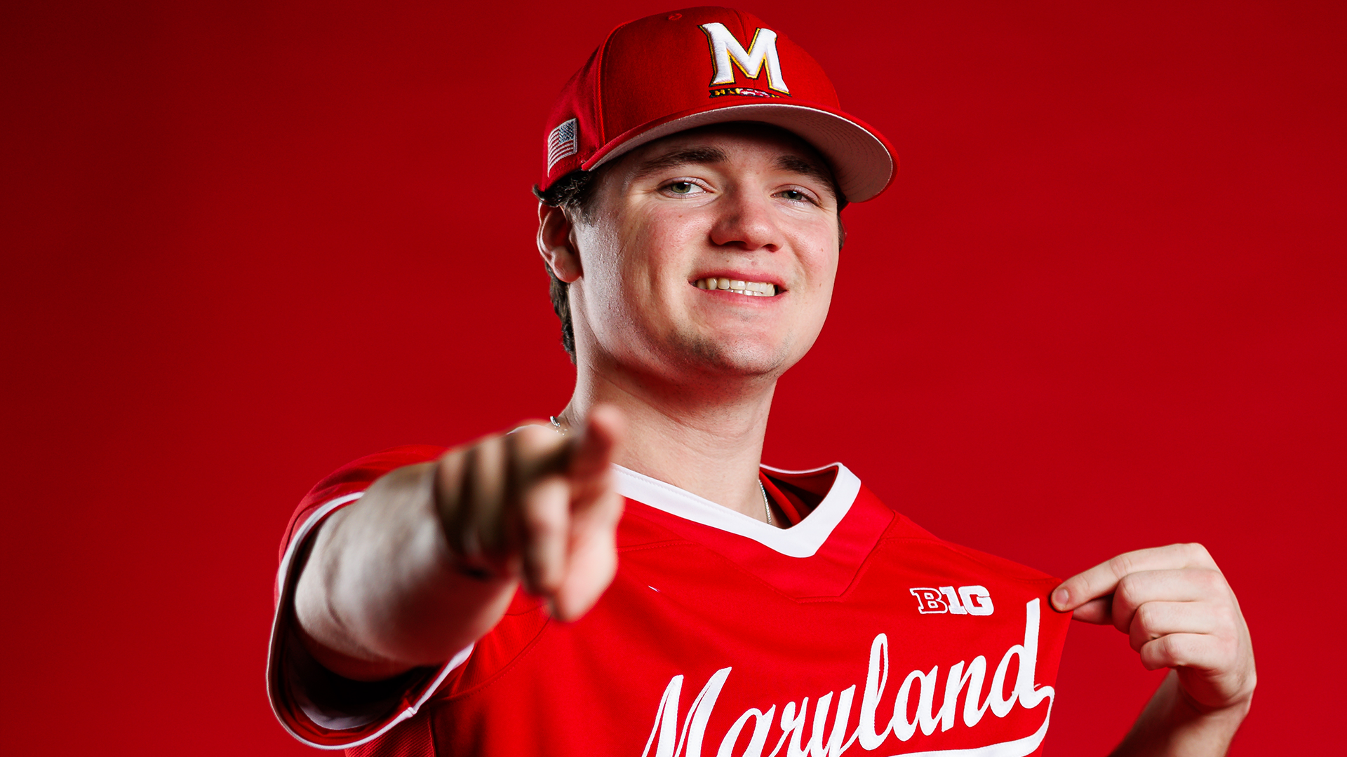 Landon Edwards Story Cover Photo - posing in front of red background pointing at camera