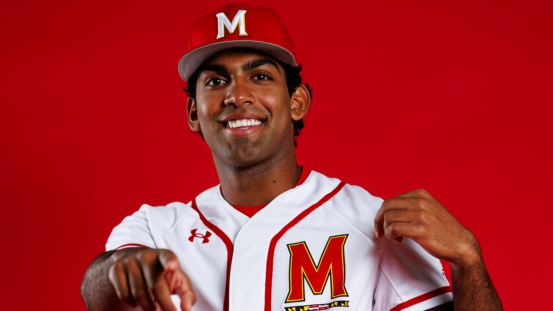 Story Cover Photo - Andrew Koshy posing in front of a red background pointing at the camera