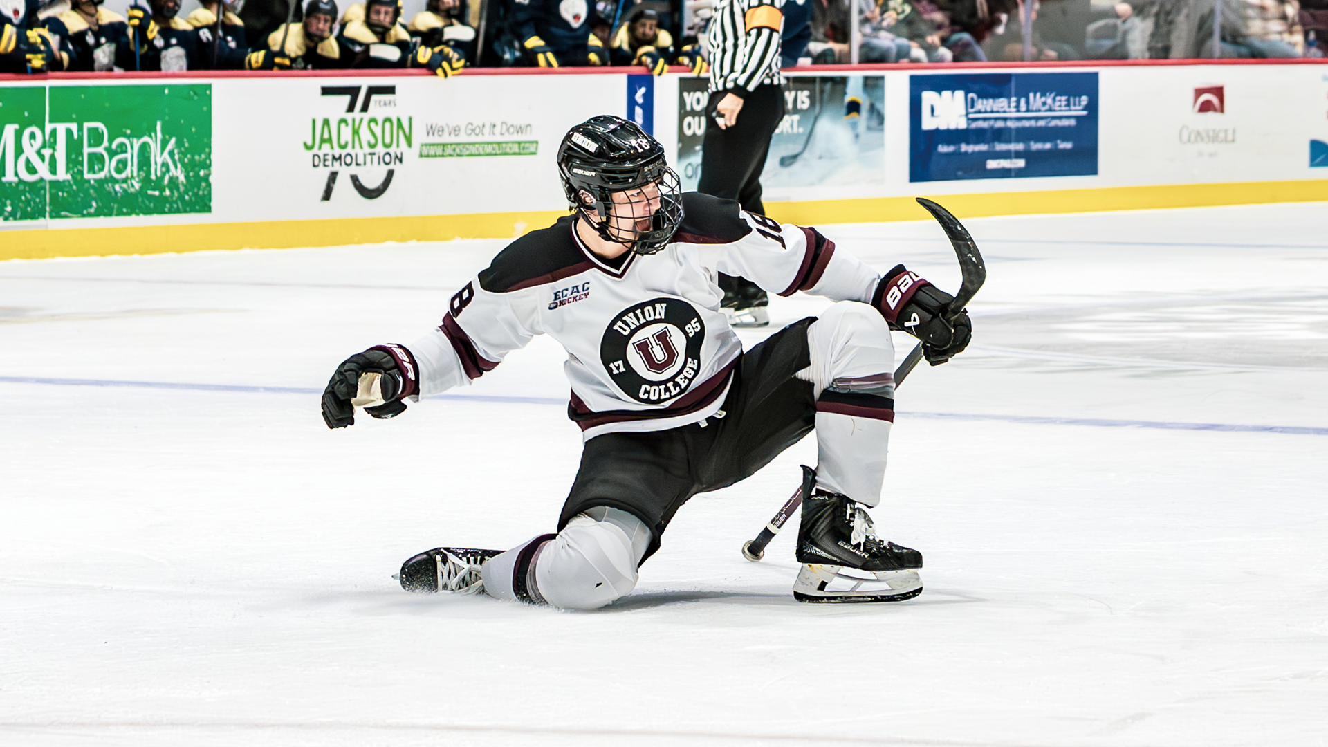a men's hocker player sliding on one knee and about to pump his fist in the air to celebrate a goal