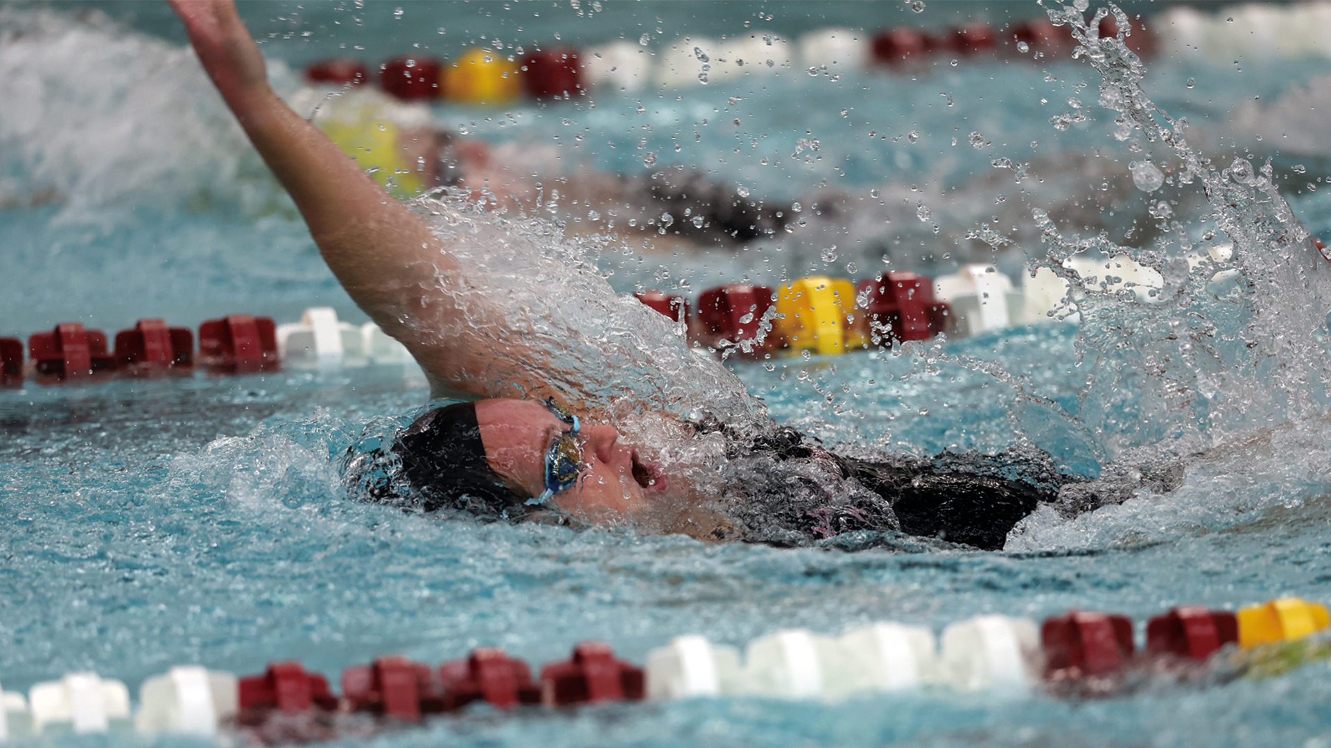 women's swimmer performing the backstroke wearing a black swim cap