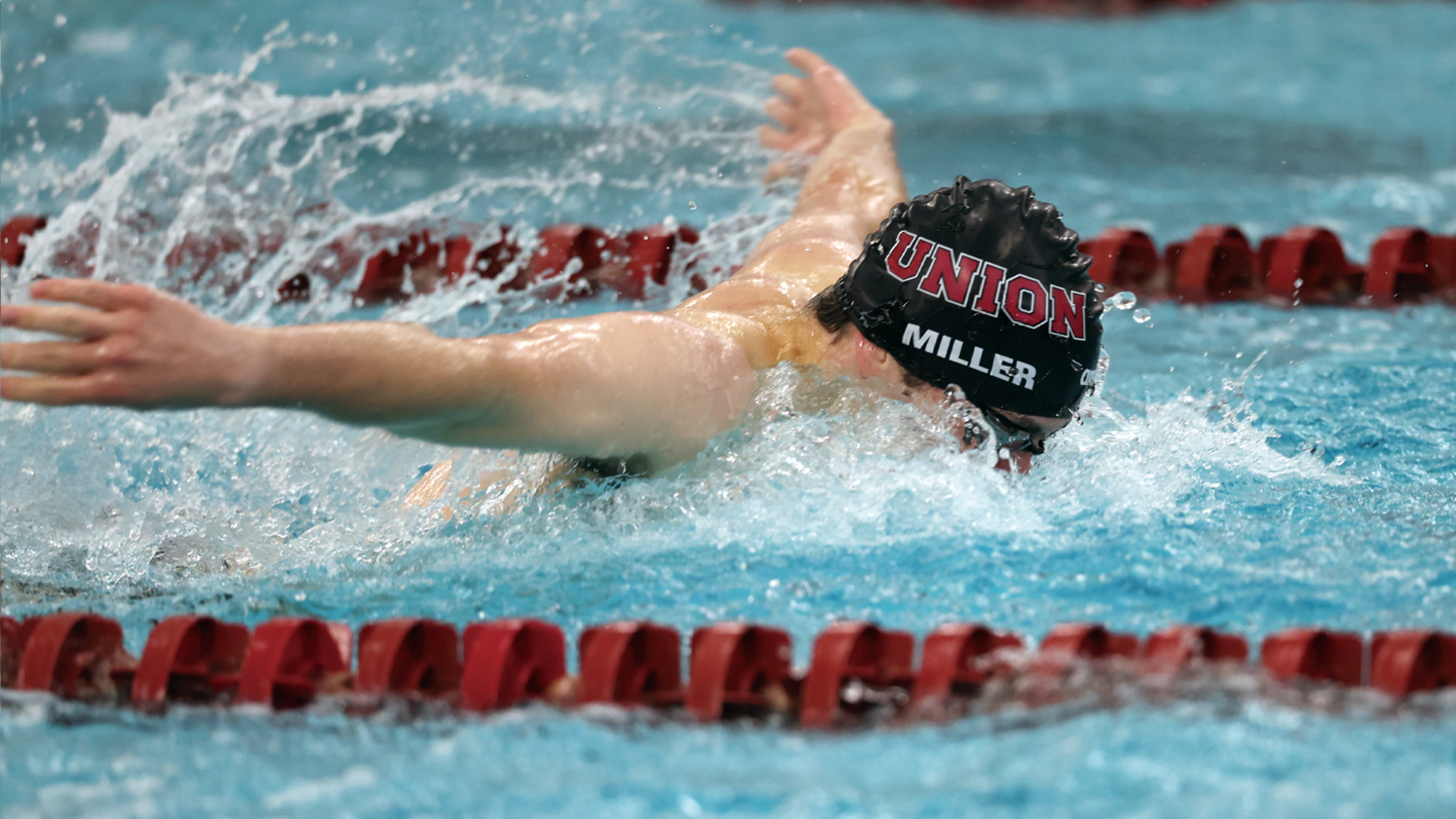men's swimmer performing the butterfly stroke, wearing a black swim cap that reads 