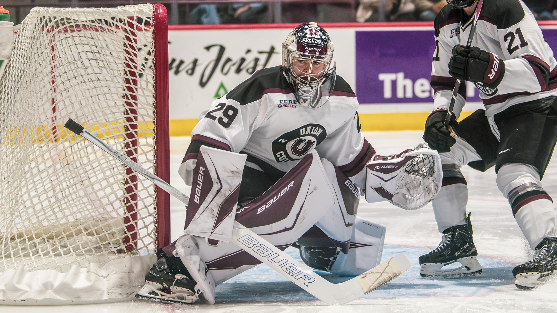 men's hockey goalie in a crouch, defending his stick-side post