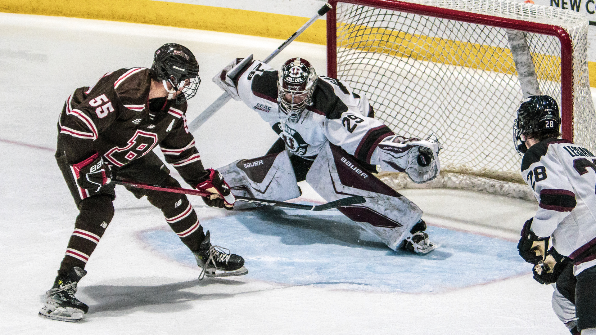 men's hockey goalie reaching to his left with his glove wide open and the puck deep in the pocket