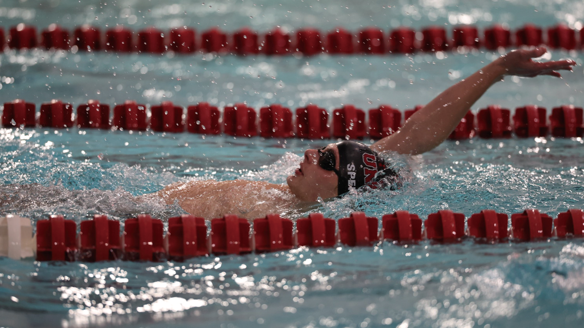 men's swimmer performing the backstroke, swimming from left to right