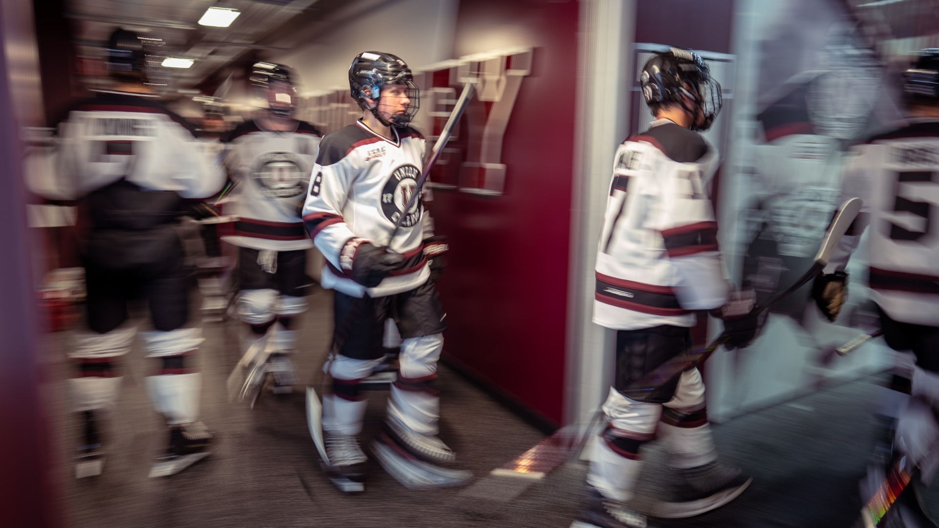 a photo of hockey players walking through the tunnel to the ice, with motion blur on the players and walls