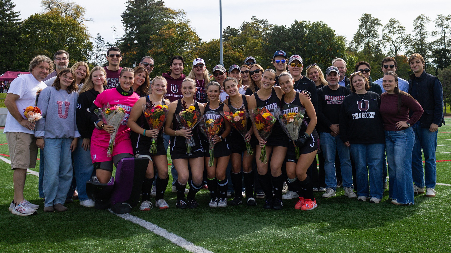 Field hockey players with their families smiling.