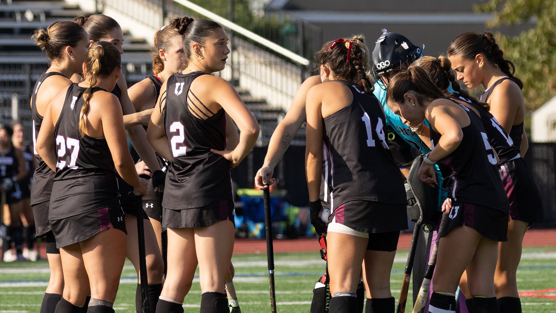 Field hockey players huddle together to talk about a play.