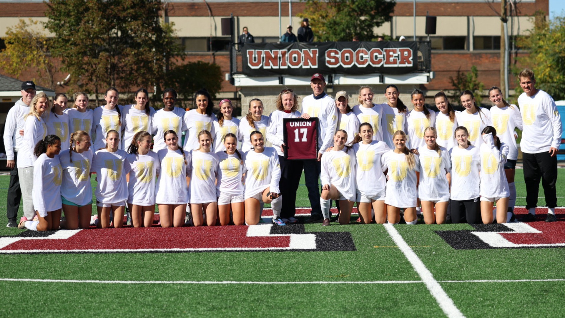 Members of the Union women's soccer team pose with Lizzie Dankert's parents and a framed 17 jersey