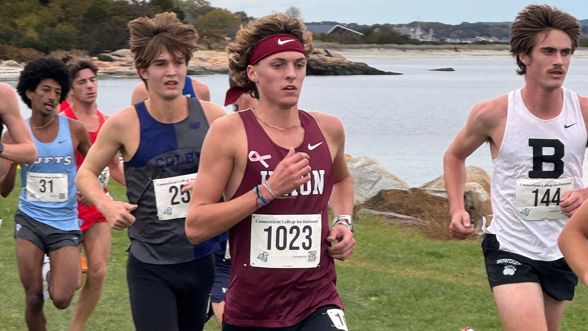 A group of cross country runners race with the ocean in the background.