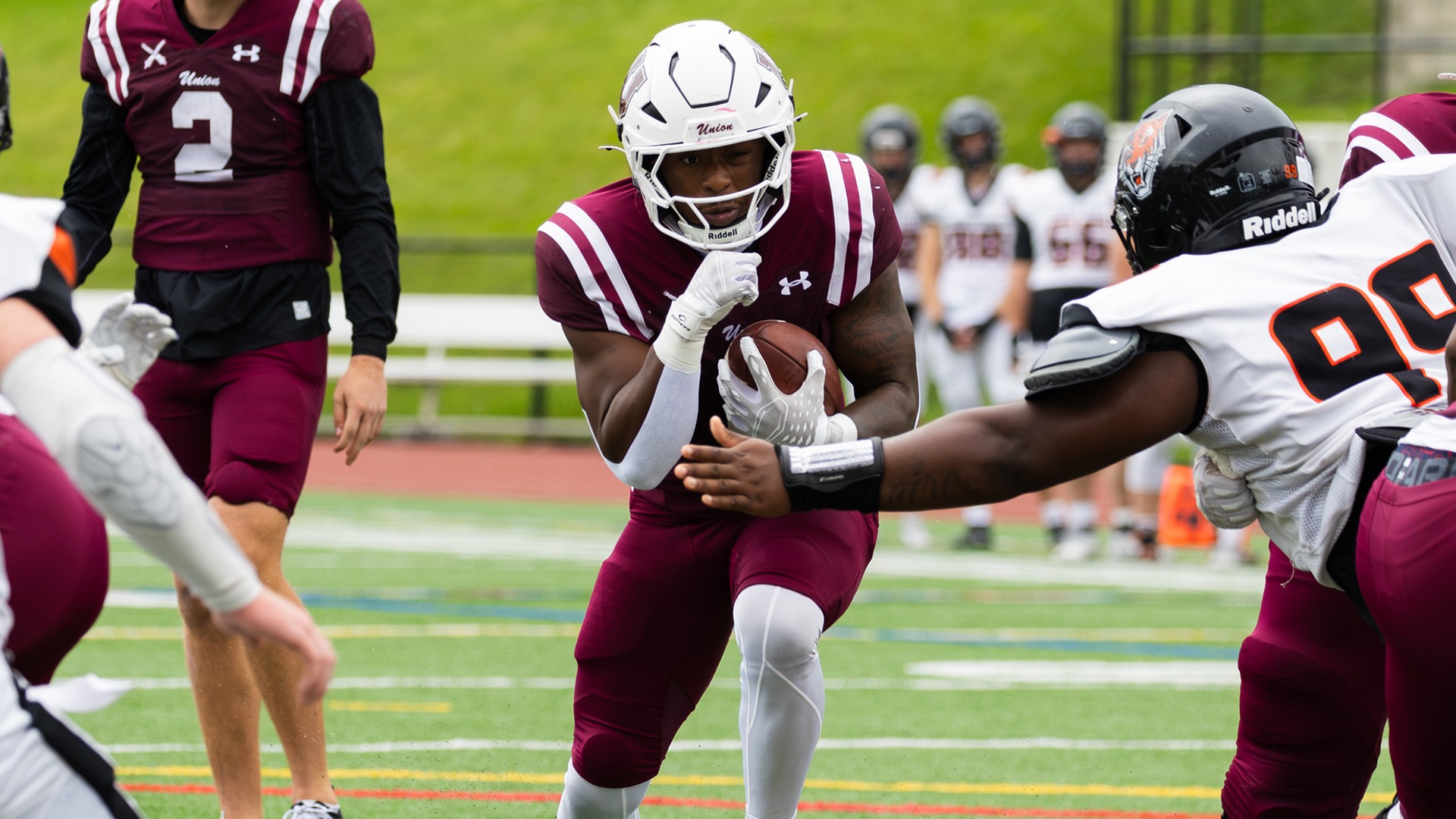 A Union football running back runs through a hole in the defensive line.