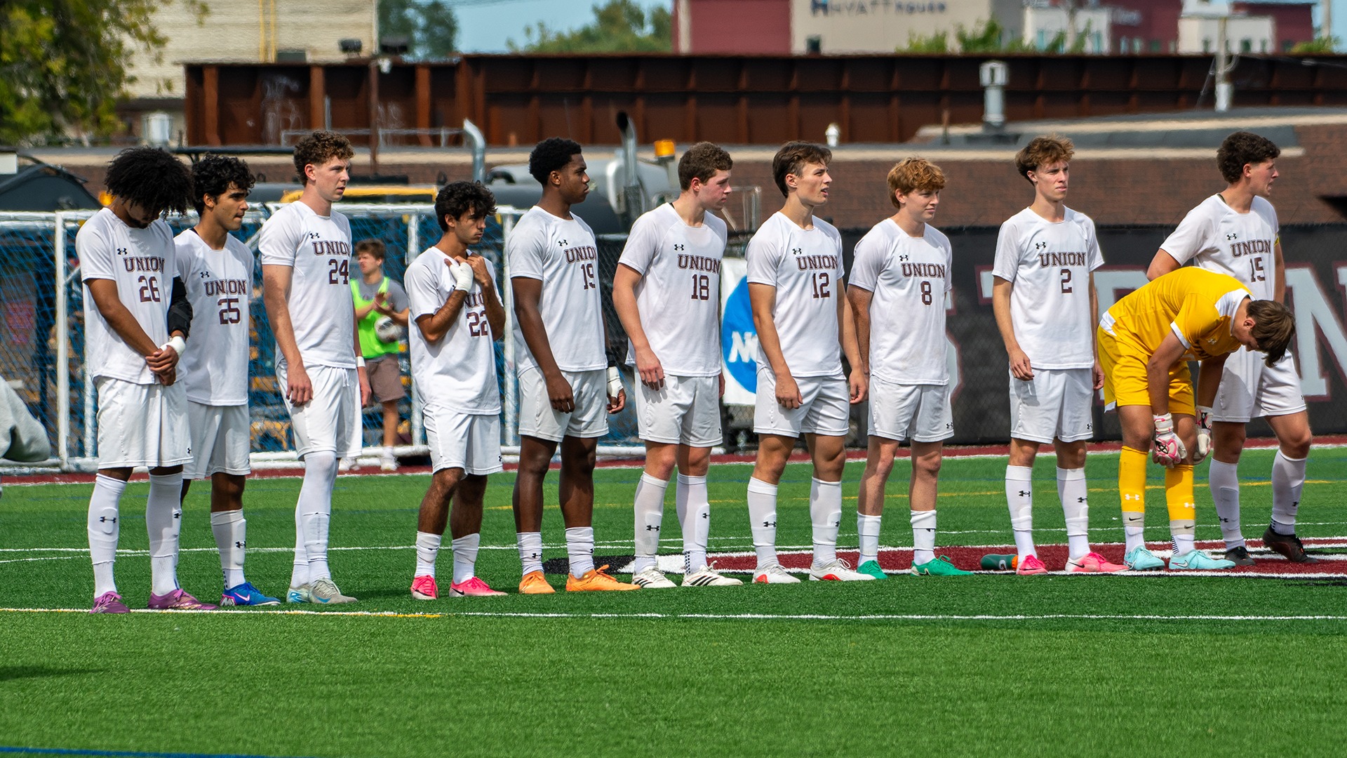 Men's soccer players lining up at midfield before the start of a game.