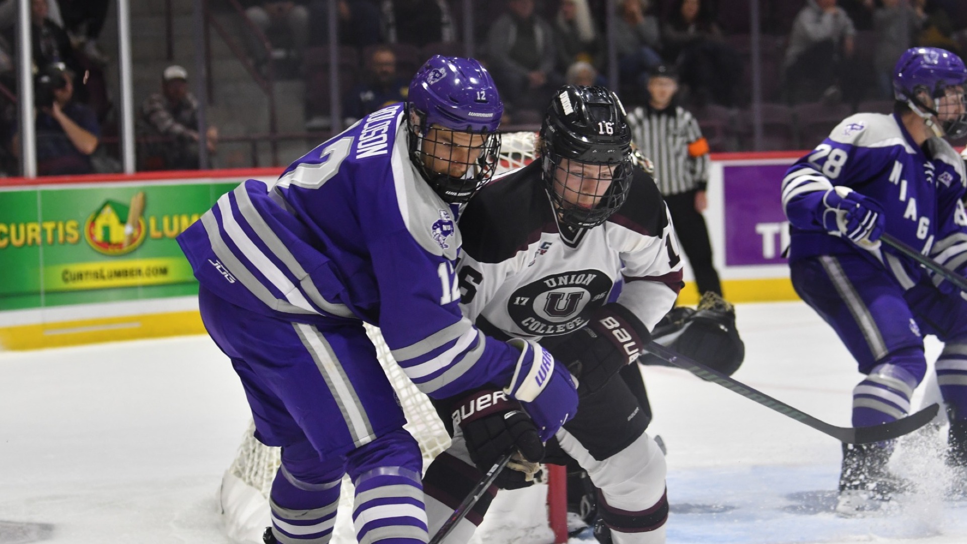 two men's hockey players shoulder-to-shoulder battling for a puck