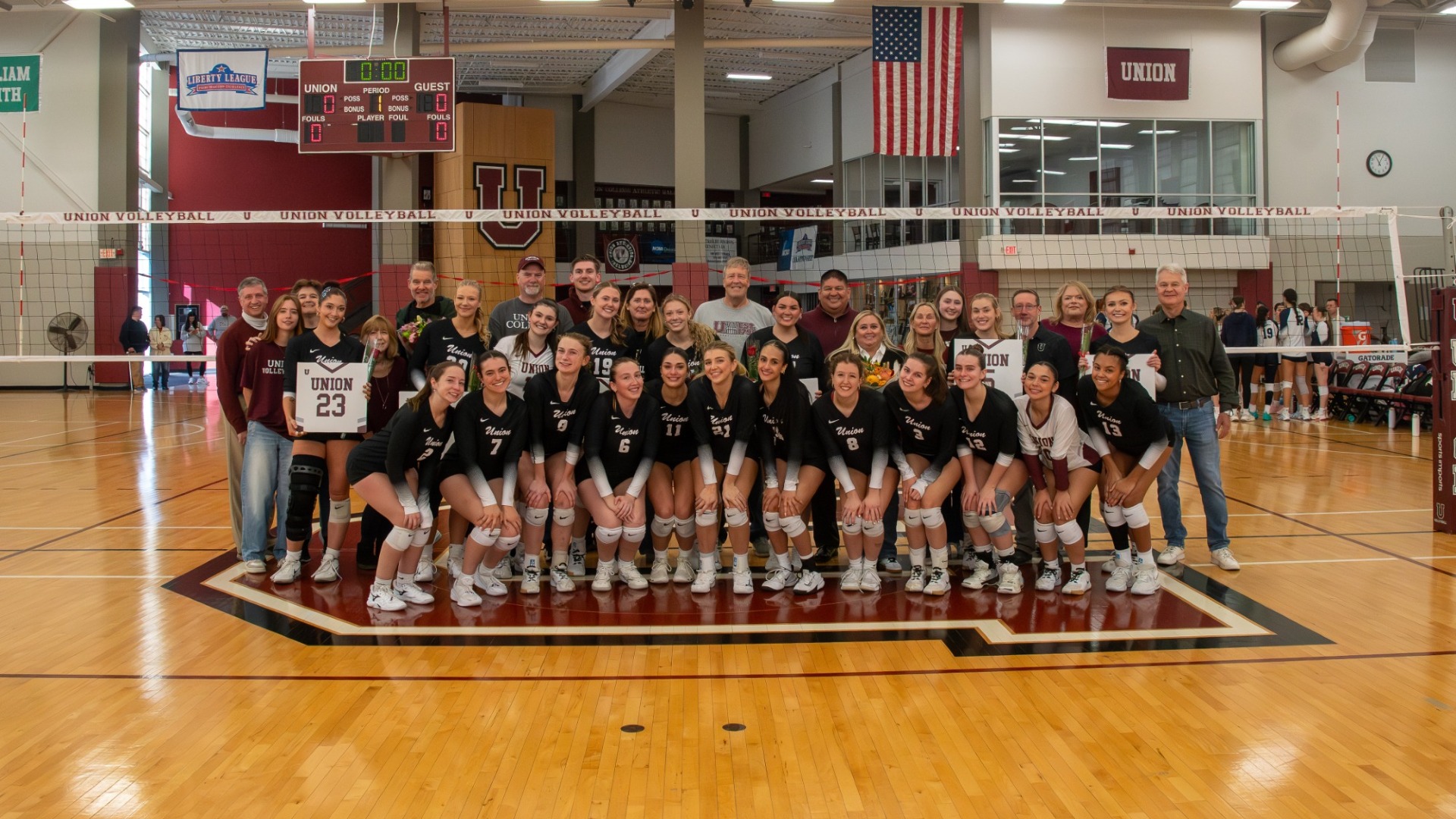 a group picture of a volleyball team with their families posing and smiling for the camera