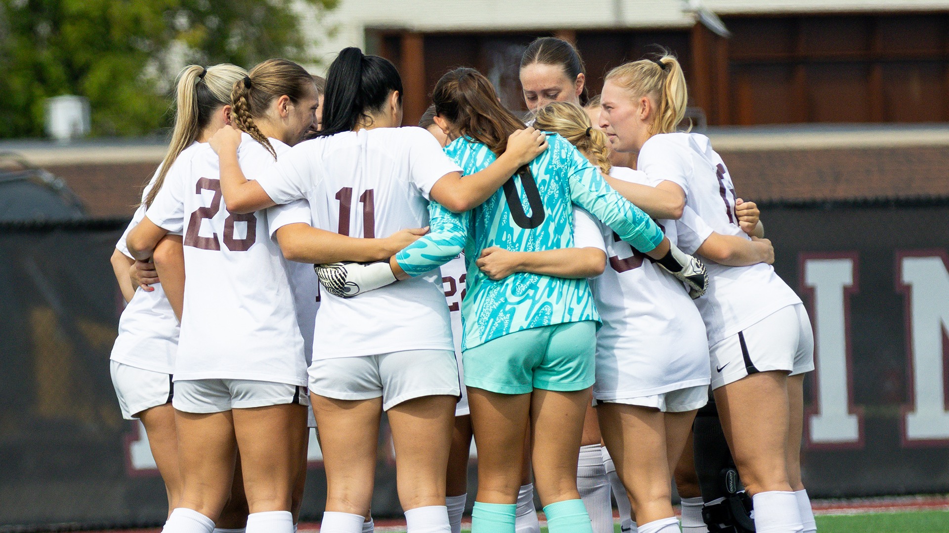 Women's soccer players huddle together before a game.