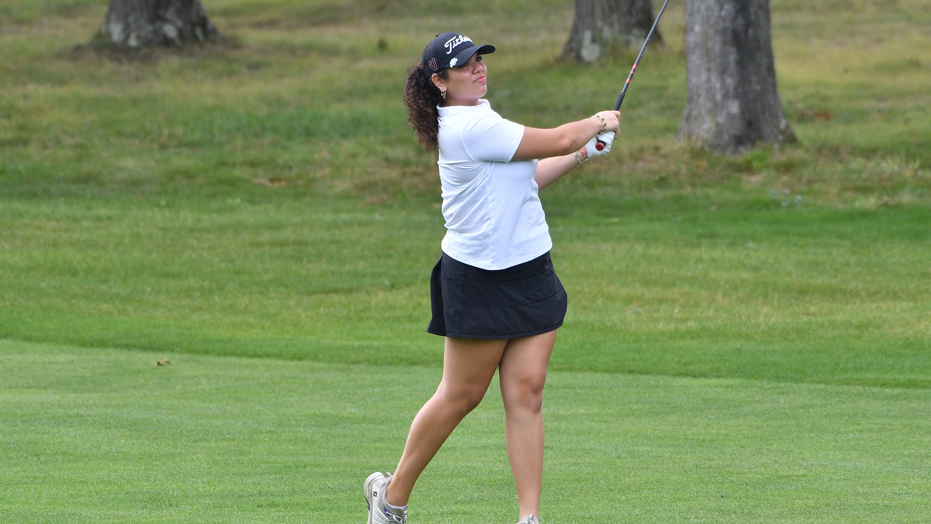 A women's golfer follows through on an iron shot from the fairway.